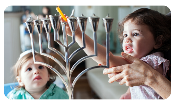 Two young children lighting a Hanukkah menorah