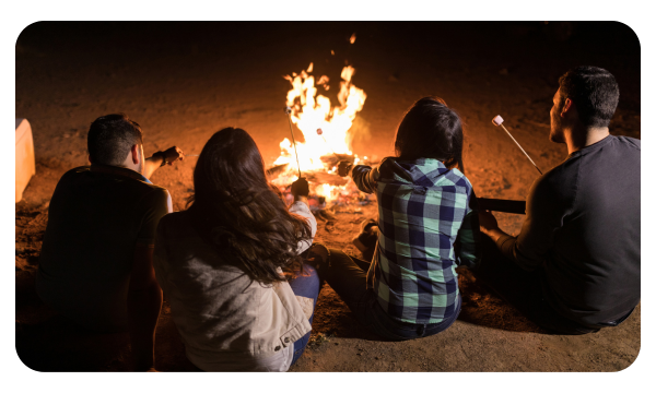 Friends sit around a bonfire roasting marshmallows