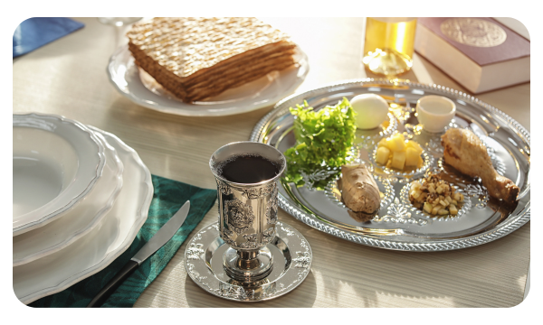 Picture of a table set for Passover with a kiddush cup, seder plate, and matzah