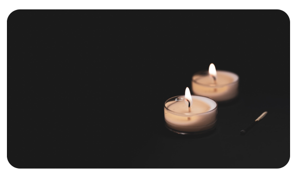 Two candles burn against a black background