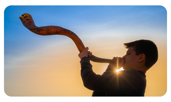 Boy playing the shofar as the sun sets