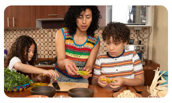 Adult cooking dinner with two children