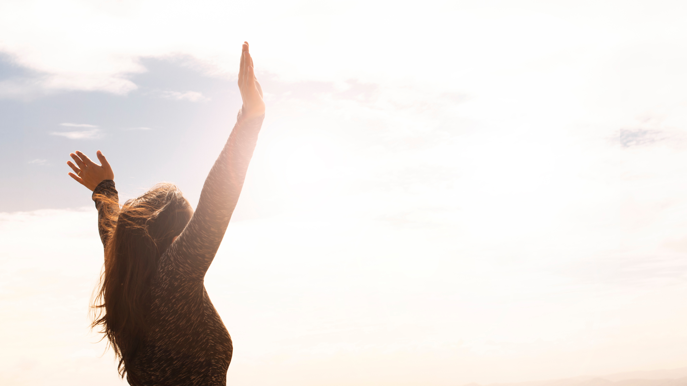 Woman throwing her hands up at the sky like she's free